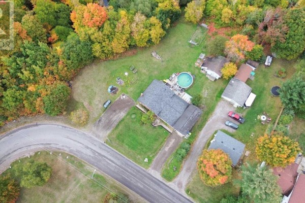Overhead view of a property with a house, outbuildings, mature trees, and a winding driveway. - 480 Moss Rd, Sault Ste  Marie