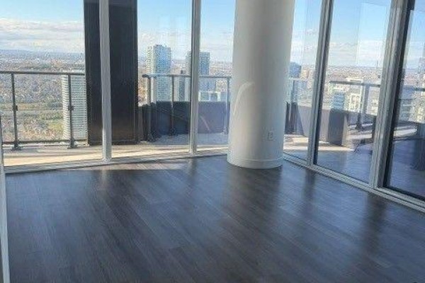 Living area with dark wood floors, floor-to-ceiling windows, and balcony access. - 4805 - 448 Burnhamthorpe Road W, Mississauga