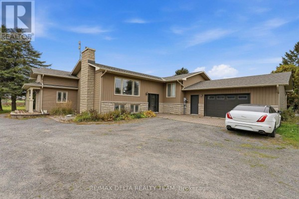 Exterior front view of a beige house with a stone base, garage, and a white luxury car parked on the driveway. - 4806 Frank Kenny Road, Ottawa