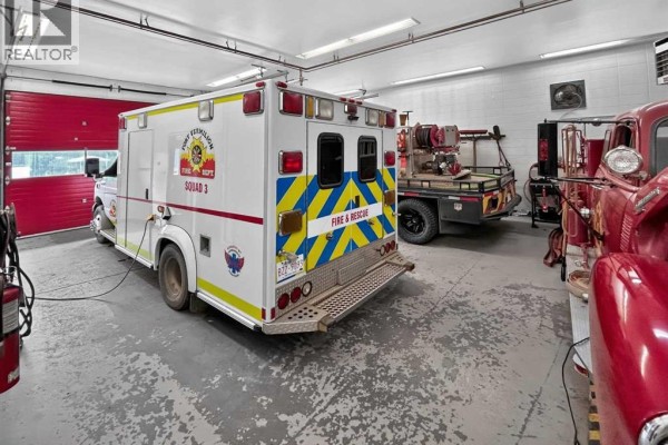 Interior shot of a fire hall garage with an ambulance, a flatbed truck, and vintage fire engine. - 4808 50 Street, Fort Vermilion