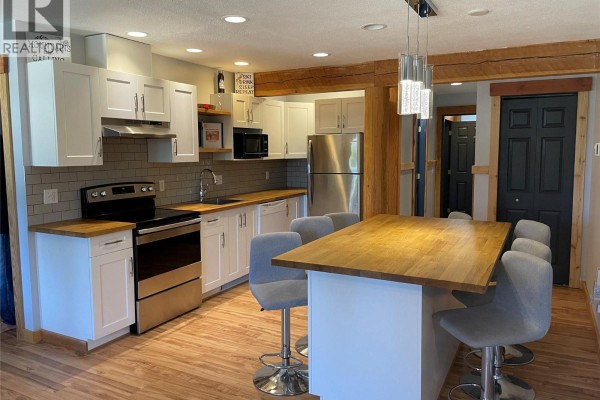 Kitchen island with bar stools and a dining area adjacent to the kitchen. - 4809 Snow Pines Road Unit# D, Big White
