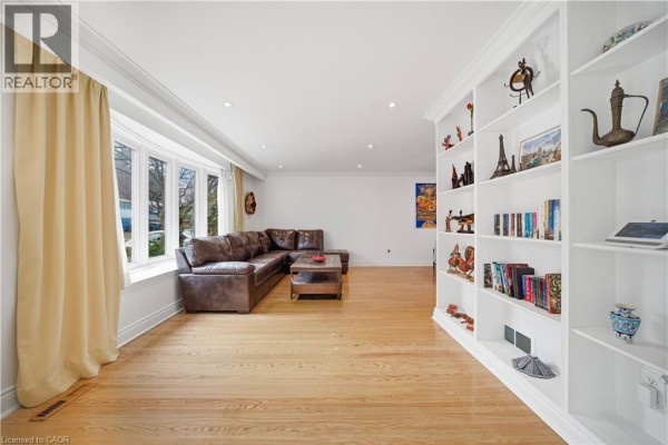 Living room with hardwood floors, a large sectional sofa, and a floor-to-ceiling bookshelf. - 481 Anthony Drive, Oakville