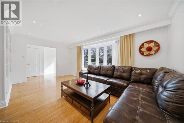 Living room with a bay window, sectional sofa, coffee table, and entryway to the left. - 481 Anthony Drive, Oakville