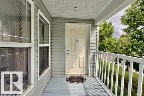 View of the front door and windows on the porch of the light blue house. - 4810 48 Av, Wetaskiwin