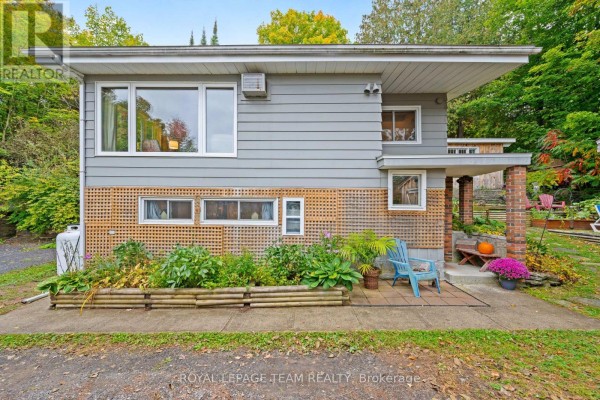 Front exterior of the house showing grey siding and brick accents. - 4819 Opeongo Road, Ottawa