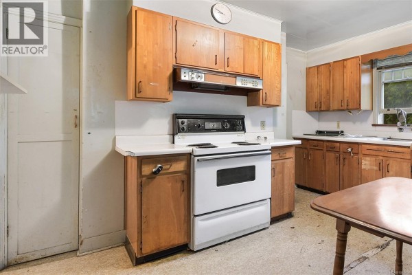 Interior kitchen with honey-colored wood cabinets, white countertops, and a white stove. - 482 Ker Ave, Saanich