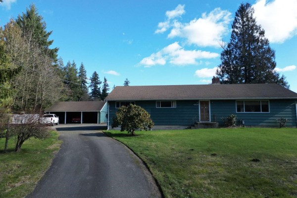Street view of the green house with a detached garage and driveway. - 4824 248 Street, Langley