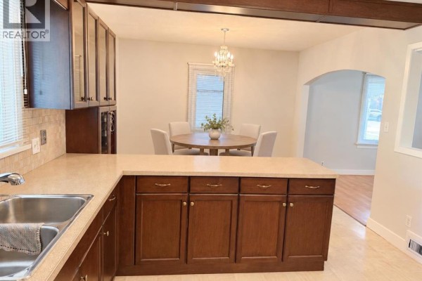 Kitchen island with dark wood cabinets and a sink, overlooking a dining area. - 4825 51 Avenue, Taber