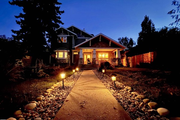 Front view of the house at night with pathway lights illuminating the walkway to the porch. - 4825 Ada Bv Nw, Edmonton