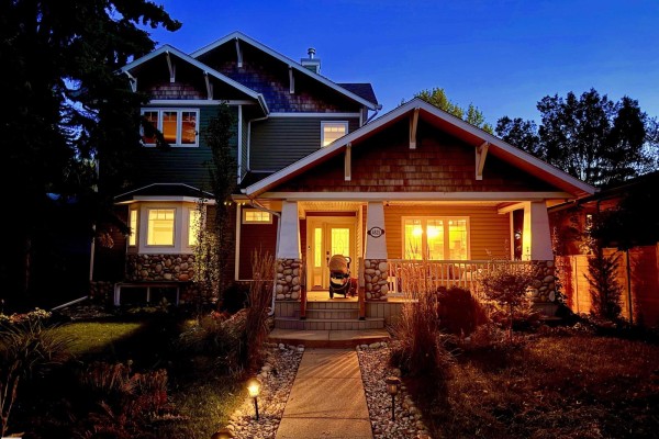 Twilight view of the house entrance, featuring a covered porch with bright interior lighting. - 4825 Ada Bv Nw, Edmonton