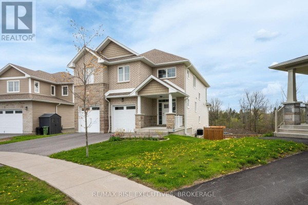 Dining area with a modern table, white walls, and large windows overlooking trees. - 483 Beth Crescent, Kingston