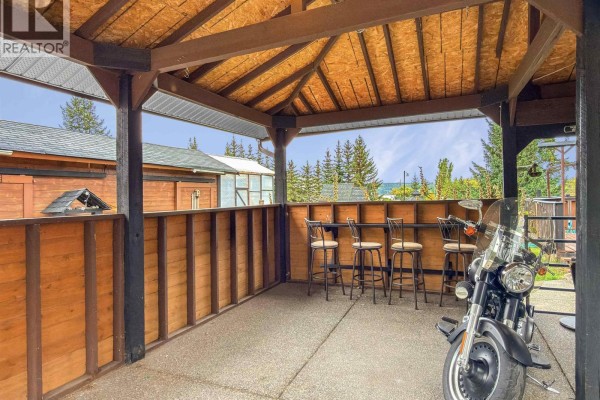 Covered patio area with seating, tables, and a motorcycle. - 4832 Clarke Avenue, Lac La Hache