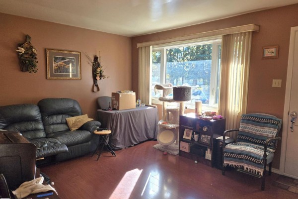 Living room with a brown leather sofa, armchair, and a large window. - 4835 47 St, Thorsby