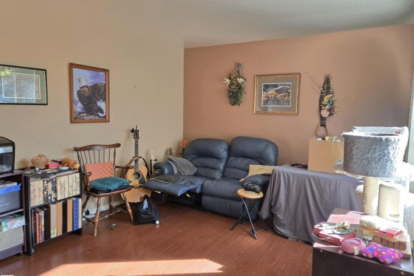 Living room with a blue recliner sofa, wooden chair, and musical instruments. - 4835 47 St, Thorsby