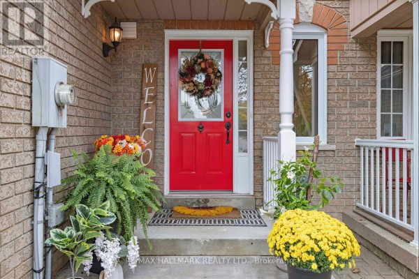 Close-up of the townhouse front door with a welcome wreath and decorative plants. - 484 Bartholemew Drive, Newmarket