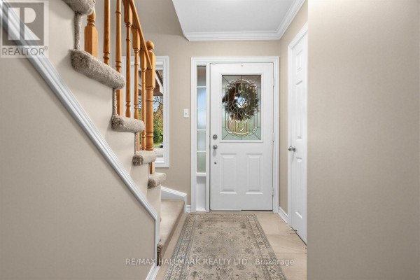 Interior view of the foyer with a staircase, a white door, and a rug. - 484 Bartholemew Drive, Newmarket