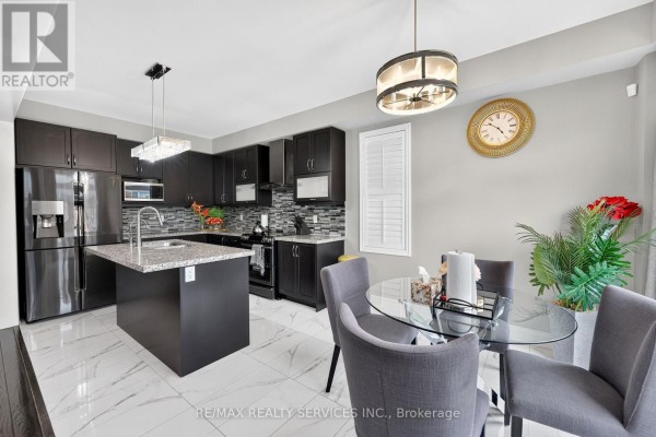 Modern kitchen with dark cabinets, island, stainless steel fridge, and dining table - 484 Greenwood Drive Essa