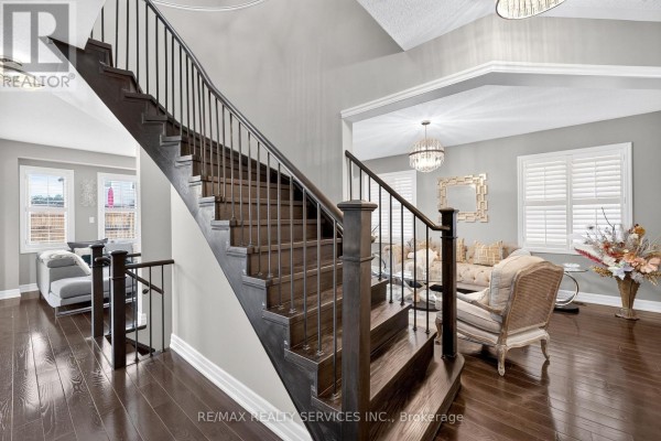 Curved staircase with wrought iron banisters and dark wood floors - 484 Greenwood Drive Essa