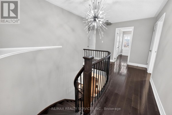 Hallway with curved staircase, dark hardwood floors, and modern chandelier - 484 Greenwood Drive Essa