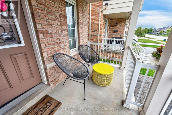 Front porch seating area with two black chairs, a yellow table, and a brown door. - 484 Greenwood Drive, Essa