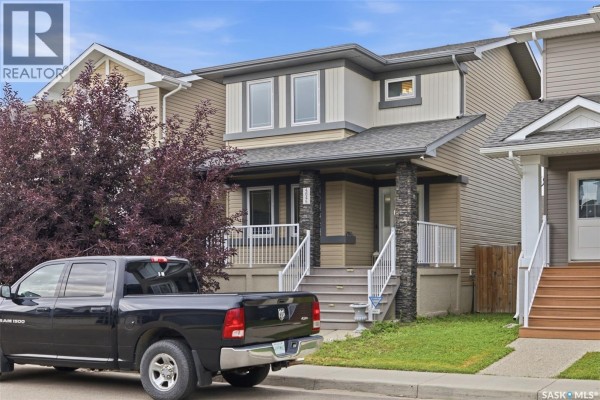 Front exterior of a two-story house with a covered porch, stone pillars, and a parked truck. - 4845 Liberty Street, Regina