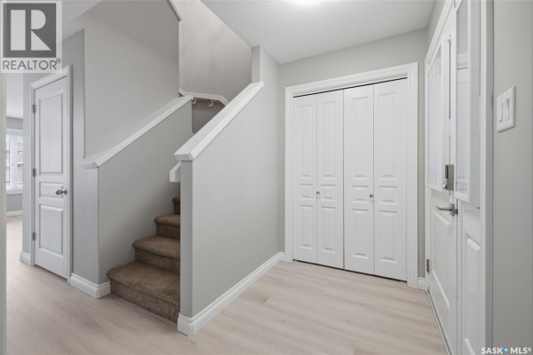 Interior hallway with light gray walls, beige carpeted stairs, and white doors. - 4845 Liberty Street, Regina