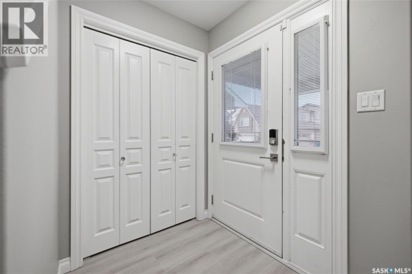 Interior entryway with light gray walls, white bi-fold closet doors, and a glass-paneled front door. - 4845 Liberty Street, Regina