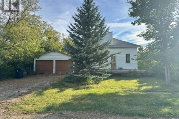 Front view of a white house with a sloped roof and a two-car garage. - 485 3rd Avenue, Lajord Rm No  128
