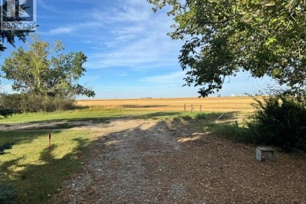 Gravel driveway leads to a large field with a bright blue sky. - 485 3rd Avenue, Lajord Rm No  128