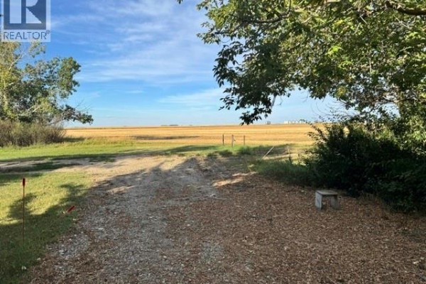 View of a rural landscape with a gravel driveway and harvested fields. - 485 3rd Avenue, Lajord Rm No  128