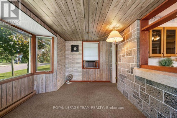 Living room with beige carpet, beige walls, and a large window with a view of houses. - 485 Fred Street, North Dundas