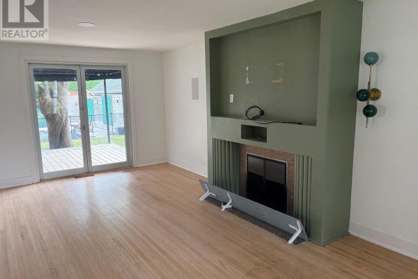 Living room with hardwood floors, fireplace, and sliding glass doors to backyard deck. - 485 Regent Street, London East