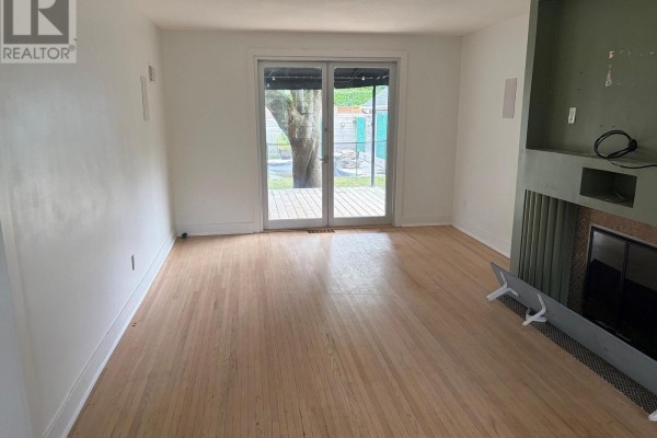 Living room with hardwood floors, fireplace, and sliding glass doors to backyard. - 485 Regent Street, London East