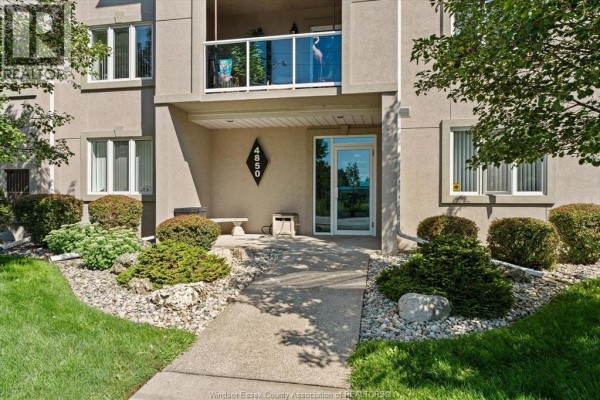 Modern kitchen with dark blue cabinets, granite countertops, stainless steel appliances, and island with stools. - 4850 Grand Boulevard Unit# 306, Windsor