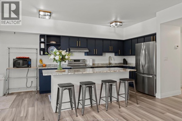 View of modern kitchen with island, bar stools, and sliding glass door to patio. - 4850 Grand Boulevard Unit# 306, Windsor