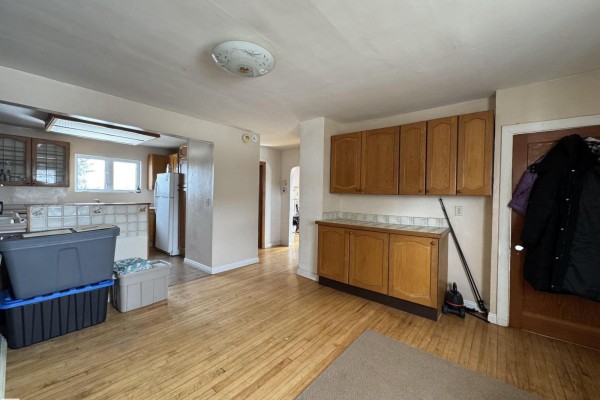 Interior view of a room with hardwood floors, wooden cabinets, and a doorway to the kitchen. - 48506 Rr 150, Rural Beaver County