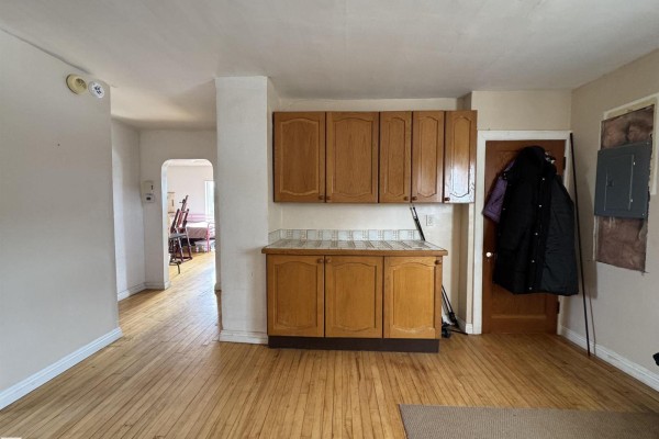 Interior view of a room with hardwood floors, wooden cabinets, and an opening to another room. - 48506 Rr 150, Rural Beaver County