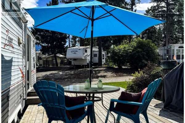 Close-up of patio chairs and table under a blue umbrella. - 4868 Riverview Drive Unit# Lot 116, Edgewater