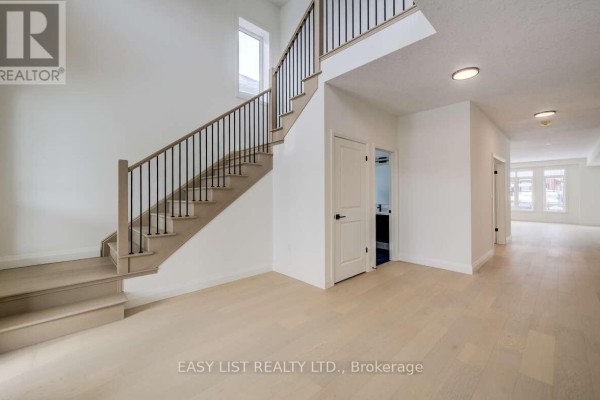 Interior view of the foyer with staircase, light wood flooring, and white walls. - 487 Black Street, Centre Wellington
