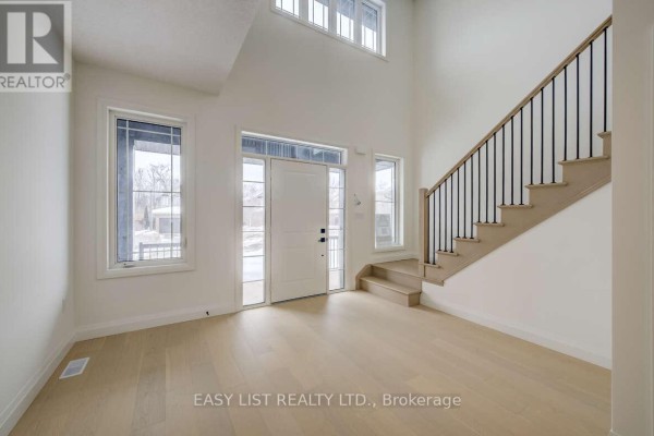 Bright entryway with large windows, front door, and staircase leading to upper level. - 487 Black Street, Centre Wellington