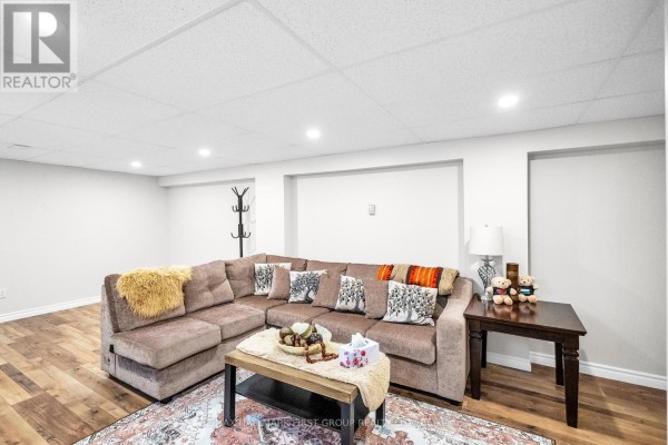 Spacious basement living room with a sectional sofa, coffee table, and a side table. - 487 Cunningham Avenue, Oshawa
