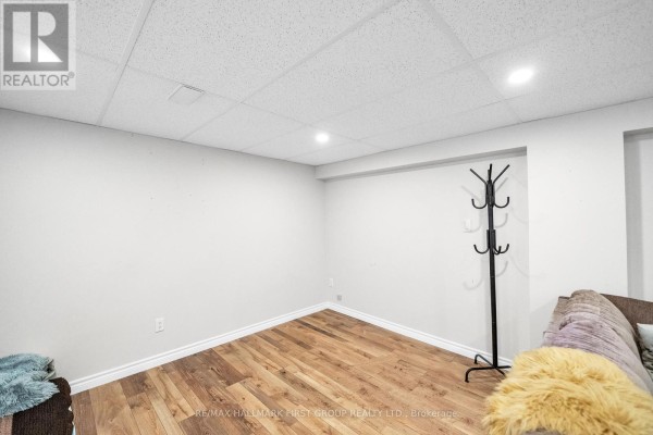 Empty basement corner with hardwood floors and a black coat rack against a white wall. - 487 Cunningham Avenue, Oshawa