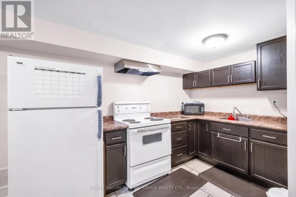 Compact kitchen with dark wood cabinets, white appliances, a stove, and a microwave. - 487 Cunningham Avenue, Oshawa