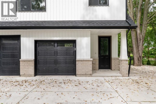Close-up of a modern white house exterior showing two black garage doors and a front entrance. - 487 Dalhousie Street, Amherstburg