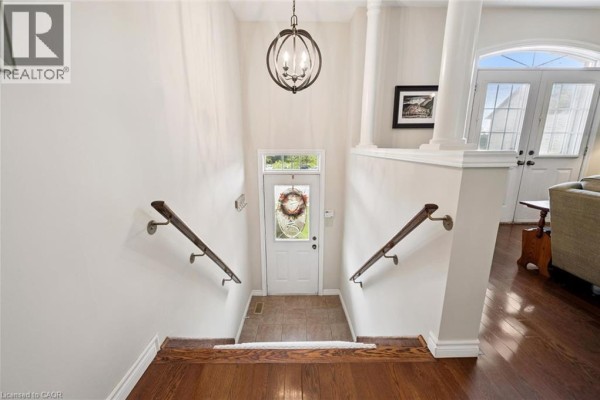 Interior entryway with wood floors, white walls, staircase, and a door with a wreath. - 487 E St Andrew Street E, Fergus
