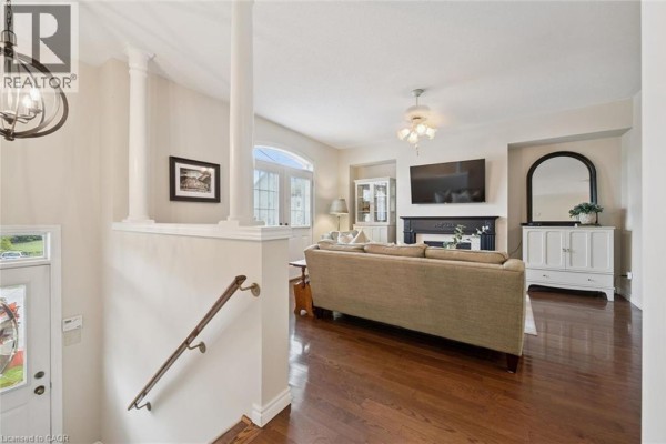 Living room with hardwood floors, a sofa, fireplace, television, and arched windows. - 487 E St Andrew Street E, Fergus