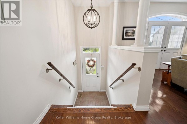 Interior foyer with stairs leading up, hardwood floors, and a front door. - 487 St Andrew Street E, Centre Wellington
