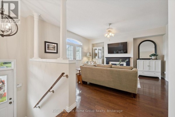 Living room with a fireplace, sofa, and hardwood floors. - 487 St Andrew Street E, Centre Wellington