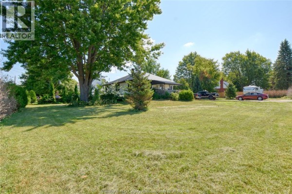 Rear view of the property showing a large recreational vehicle, trees, and houses. - 487 St Clair Street, Chatham