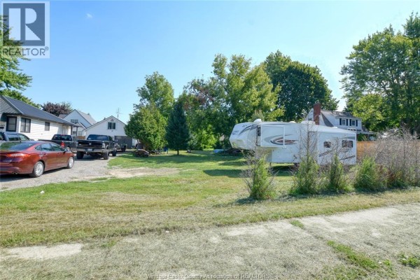 View of the detached garage with two doors, a trailer, and a pickup truck. - 487 St Clair Street, Chatham